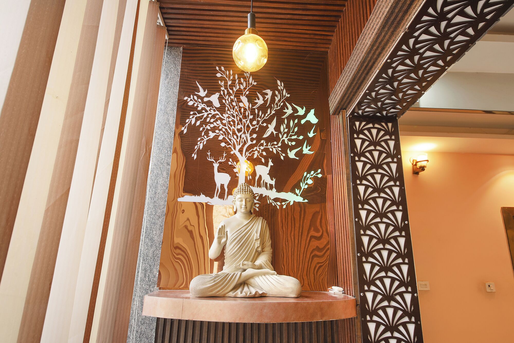 A statue of a seated figure with a tree and animals, a hanging light, and a patterned wall.