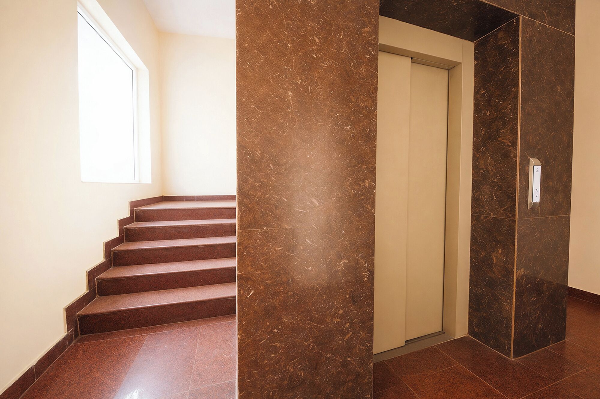 A staircase with a handrail, a door, and a wall with a marble-like texture.