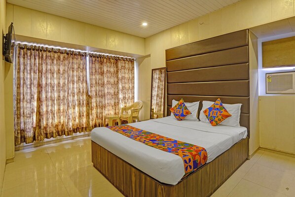 A hotel room with a large bed, a wooden headboard, and a window with curtains. - Via Lal Sai Residency (Mumbai)