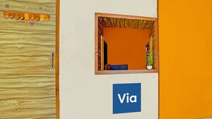 Una zona d'entrada amb una porta de fusta, una finestra amb vistes i un rètol que diu 'Via'.