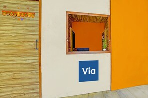 A reception area with a wooden door, a window with a view, and a 'Via' sign. - Via Lal Sai Residency (Mumbai)