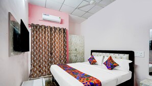 Une chambre à coucher comprenant un lit, une armoire, un appareil de climatisation et un téléviseur.