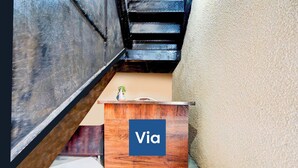 Un escalier avec une rampe en bois, un petit bureau en bois orné d’un vase et un mur à la surface texturée.