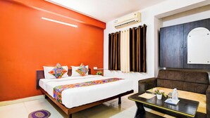 Una habitación de hotel con una cama, un sofá, una mesita y un equipo de aire acondicionado.