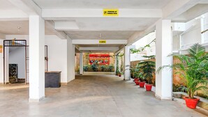 Pasillo de hotel con suelo de baldosas, plantas en macetas y un cartel que indica estacionamiento bajo la responsabilidad del propietario.