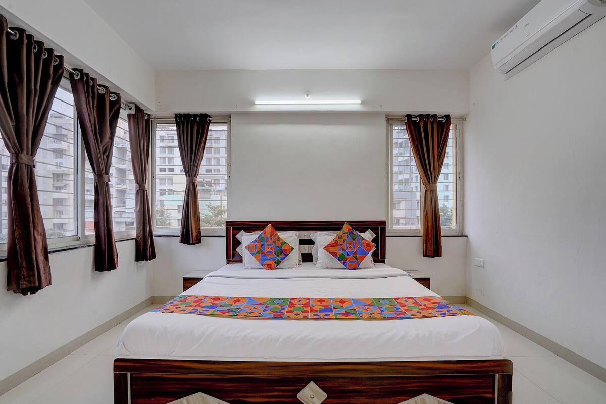 A bedroom with a wooden bed, white bedding, and geometric-patterned pillows.