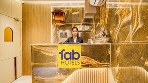 A reception desk with a marble design, a receptionist, and a statue. - Fabhotel Jk (Mumbai)