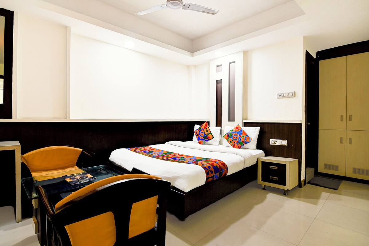 A hotel room with a bed, a desk, a chair, a wardrobe, and a ceiling fan.