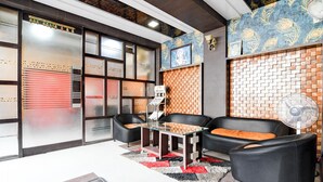 A reception area with a modern design, featuring a brick wall, a glass partition, and a seating area with black leather chairs and a glass table. - Fabhotel Park Street Inn (Ranchi)