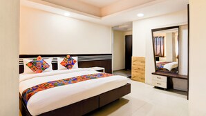 A modern hotel room with a large bed, a bedside table, a mirror, and a ceiling fan. - Fabhotel Park Street Inn (Ranchi)