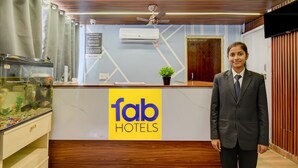 A reception desk with a logo for 'fab hotels', a ceiling fan, an air conditioning unit, and a fish tank.