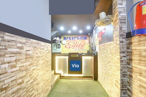 Un espace d’accueil comprenant un comptoir de réception, une horloge et un panneau indiquant « Hôtel Elite ».