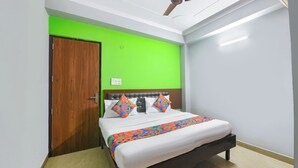 A bedroom with a bed, a wooden door, and a green wall. - Via Elite Stay (Gurugram)