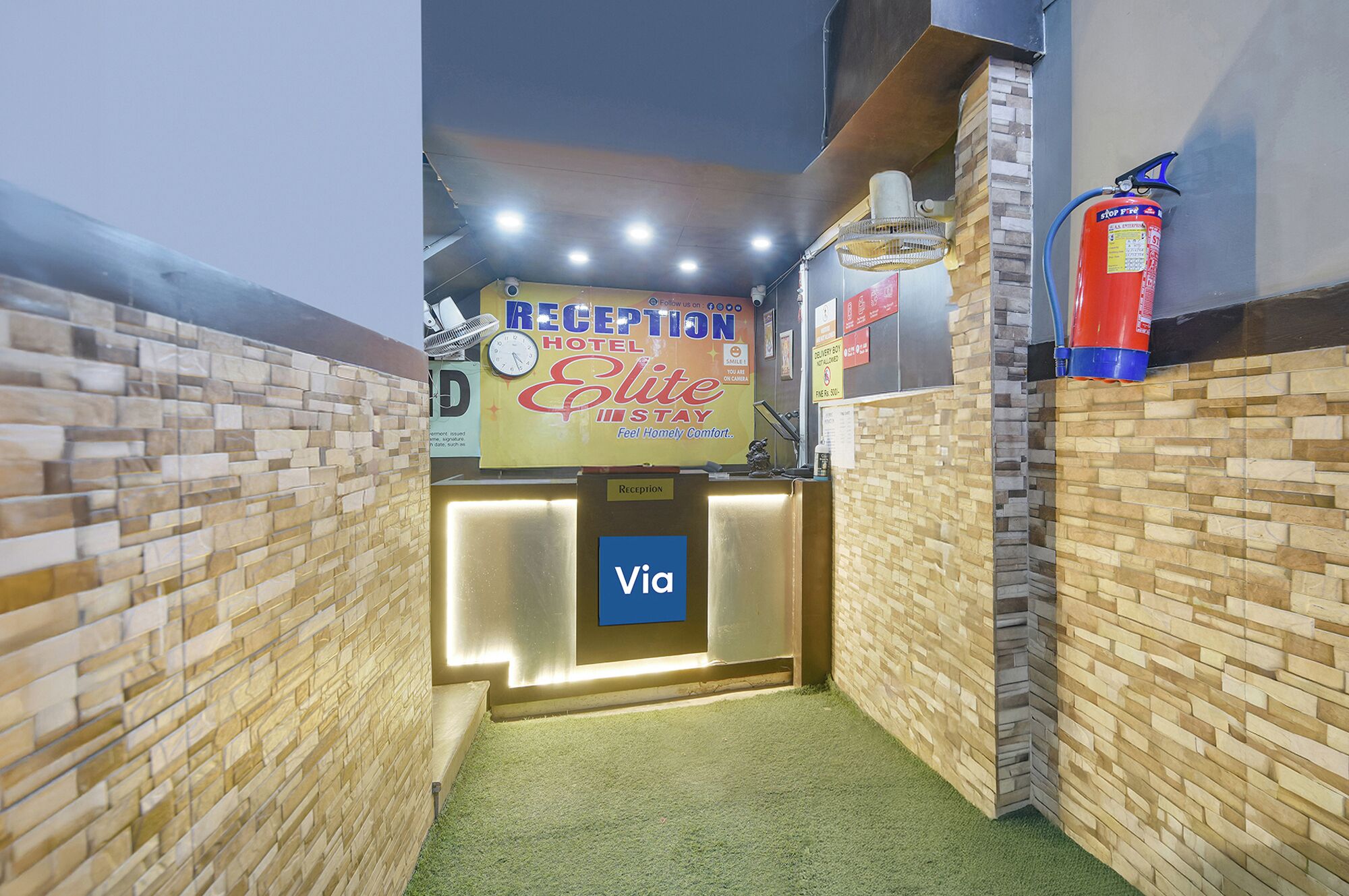 A reception area with a reception desk, a clock, a fire extinguisher, and a sign for the reception.