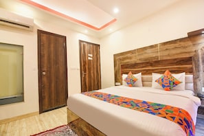 A bedroom with a large bed, wooden headboard, and colorful pillows. - Fabhotel Dev Residency (New Delhi)