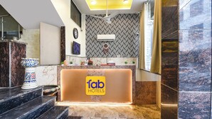 A hotel reception area with a marble counter, a ceiling fan, and a wall-mounted clock. - Fabhotel Dev Residency (New Delhi)