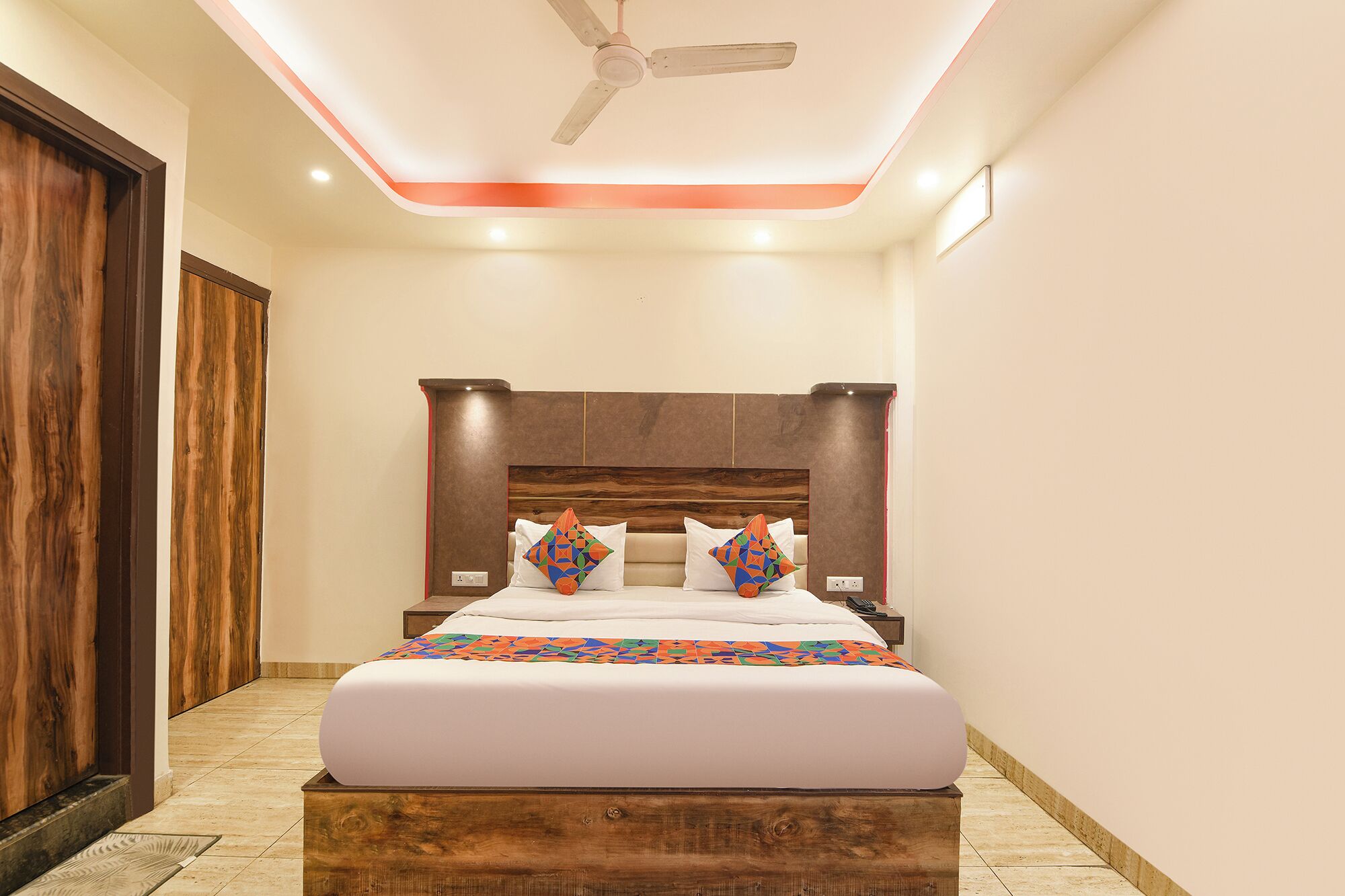 A bedroom with a wooden headboard, a bed with white bedding, and a ceiling fan.