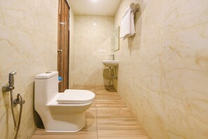 A narrow bathroom with a toilet, a shower, and a sink. - Fabhotel Dev Residency (New Delhi)