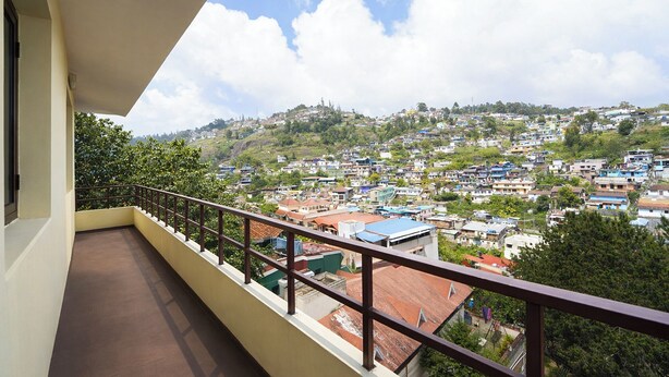 A balcony with a view of a hillside town. - Via Yellow Mist Home Stay (Kodaikanal)