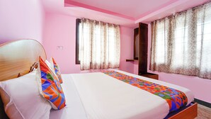 A bedroom with a wooden bed, colorful pillows, a patterned bedspread, and pink walls. - Via Yellow Mist Home Stay (Kodaikanal)