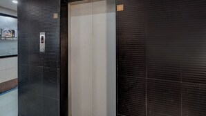 An elevator with a digital display, a closed door, and a textured wall. - Fabhotel Anjani (Ahmedabad)