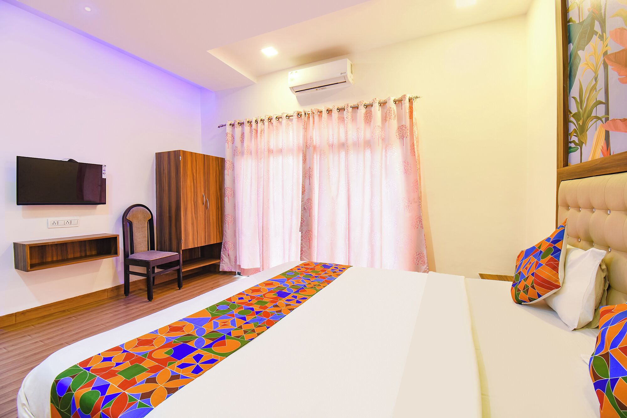 A hotel room with a bed, a TV, a wardrobe, a chair, and a window with curtains.