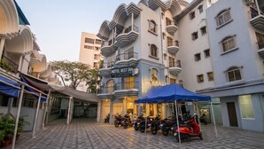 Un hotel con un letrero que dice 'HOTEL REST INN', un área de estacionamiento techada y varias motocicletas estacionadas afuera.