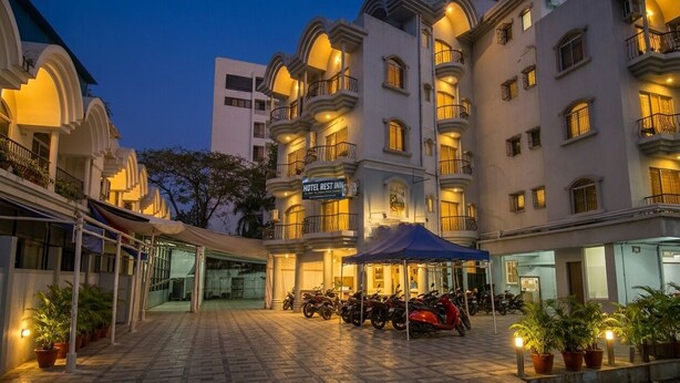 Un hotel con varios balcones, una zona de estacionamiento techada y un letrero que indica que es un hotel y posada.