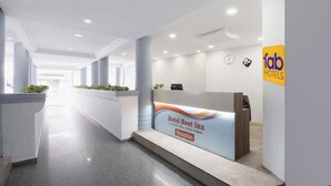Zona de recepción de un hotel con mostrador, un reloj y un cartel que indica un descanso hotelero.