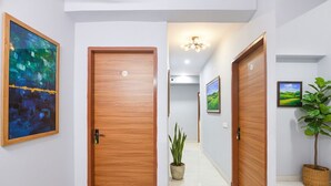 Un couloir avec des portes en bois, une plante en pot et des tableaux encadrés accrochés aux murs.