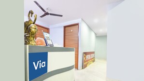 Un comptoir d’accueil avec une enseigne « Via », un ventilateur de plafond, une porte en bois et une enseigne « Imperial Residency » indiquant les équipements disponibles.