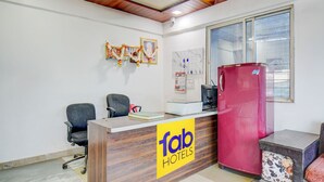 Un comptoir d’accueil avec une enseigne « Tab Hotels », un réfrigérateur rouge et une fenêtre avec des stores.