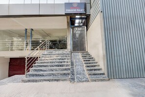 A hotel entrance with marble steps, a metal railing, and a sign above.