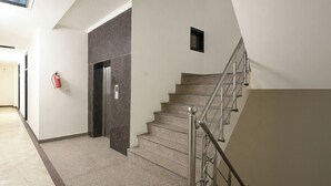 A modern interior with a staircase, a fire extinguisher, and a door leading to an elevator. - Fabhotel Sweet Inn (New Delhi)