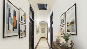 A hallway with framed artworks on the walls, a marble floor, and a wooden console table with decorative items. - Fabhotel Sweet Inn (New Delhi)
