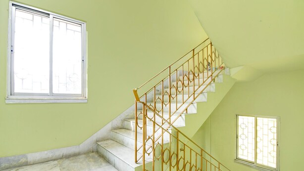 A staircase with a metal railing, a small window with bars, and a larger window with bars. - Fabhotel Florence Palace (Kolkata)