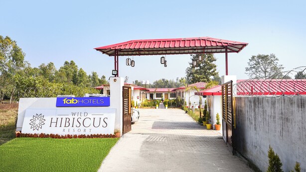 A gated entrance to Hibiscus Resort with a red roof and a signboard for FabHotels. - Fabhotel Wild Hibiscus Resort (Ramnagar)