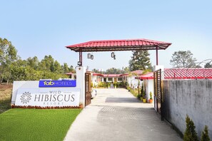 A gated entrance to Hibiscus Resort with a red roof and a signboard for FabHotels. - Fabhotel Wild Hibiscus Resort (Ramnagar)