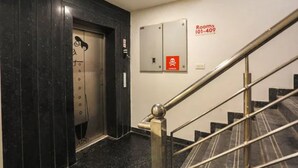 A hotel elevator with a mirrored wall and a staircase with metal railings. - Fabhotel Nishkarsh (Jaipur)