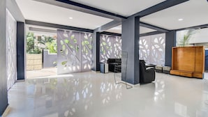 A spacious lobby with a high ceiling, a seating area with a modern chair, and a wooden cabinet. - Fabhotel Rajyog Residency (Pune)