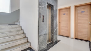 A modern interior with a marble staircase, a marble wall with a door, and two wooden doors labeled 401 and 402. - Fabhotel Rajyog Residency (Pune)