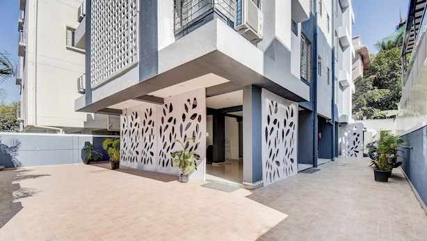 A modern building with a covered outdoor area, potted plants, and a clear sky. - Fabhotel Rajyog Residency (Pune)