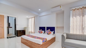 A modern bedroom with a large bed, a grey sofa, and a wardrobe. - Fabhotel Rajyog Residency (Pune)