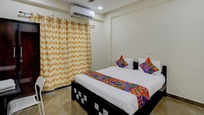 A bedroom with a bed, a desk, a chair, a wardrobe, an air conditioning unit, and a ceiling fan. - Fabhotel Heaven 75 (Hyderabad)