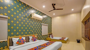 A hotel room with two beds, a ceiling fan, an air conditioning unit, and a window with a view. - Fabhotel Om Sai Residency (Varanasi)