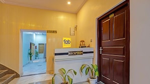 A hotel reception area with a reception desk, a check-in/out sign, and a door marked with the number 1001. - Fabhotel Om Sai Residency (Varanasi)