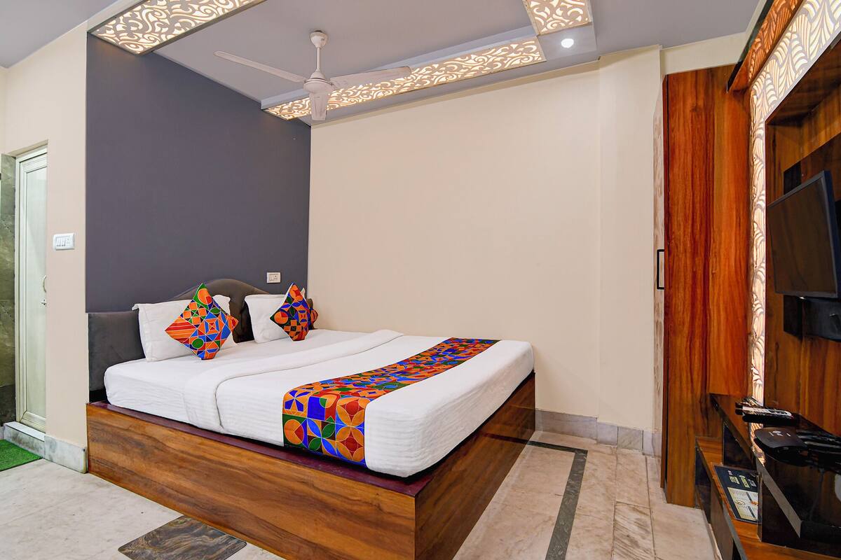 A modern bedroom with a wooden bed, a ceiling fan, and a TV on the wall.