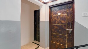 A hallway with a wooden door, a light switch, and a ceiling light fixture. - Via Rajdanga Retreat (Kolkata)