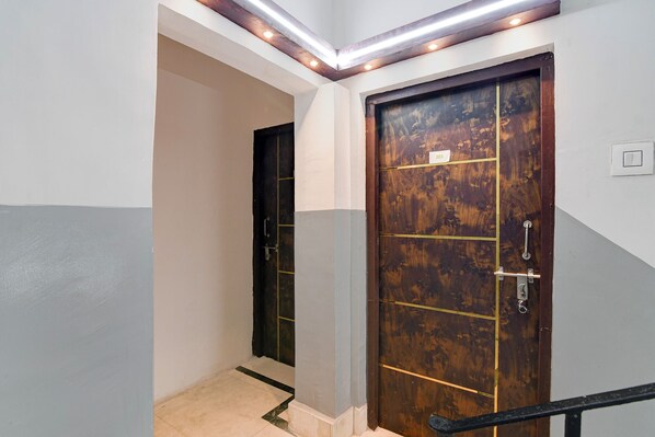 A hallway with a wooden door, a light switch, and a ceiling light fixture. - Via Rajdanga Retreat (Kolkata)