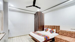 Un dormitorio con una cama, un sofá, un ventilador de techo y un armario de madera.